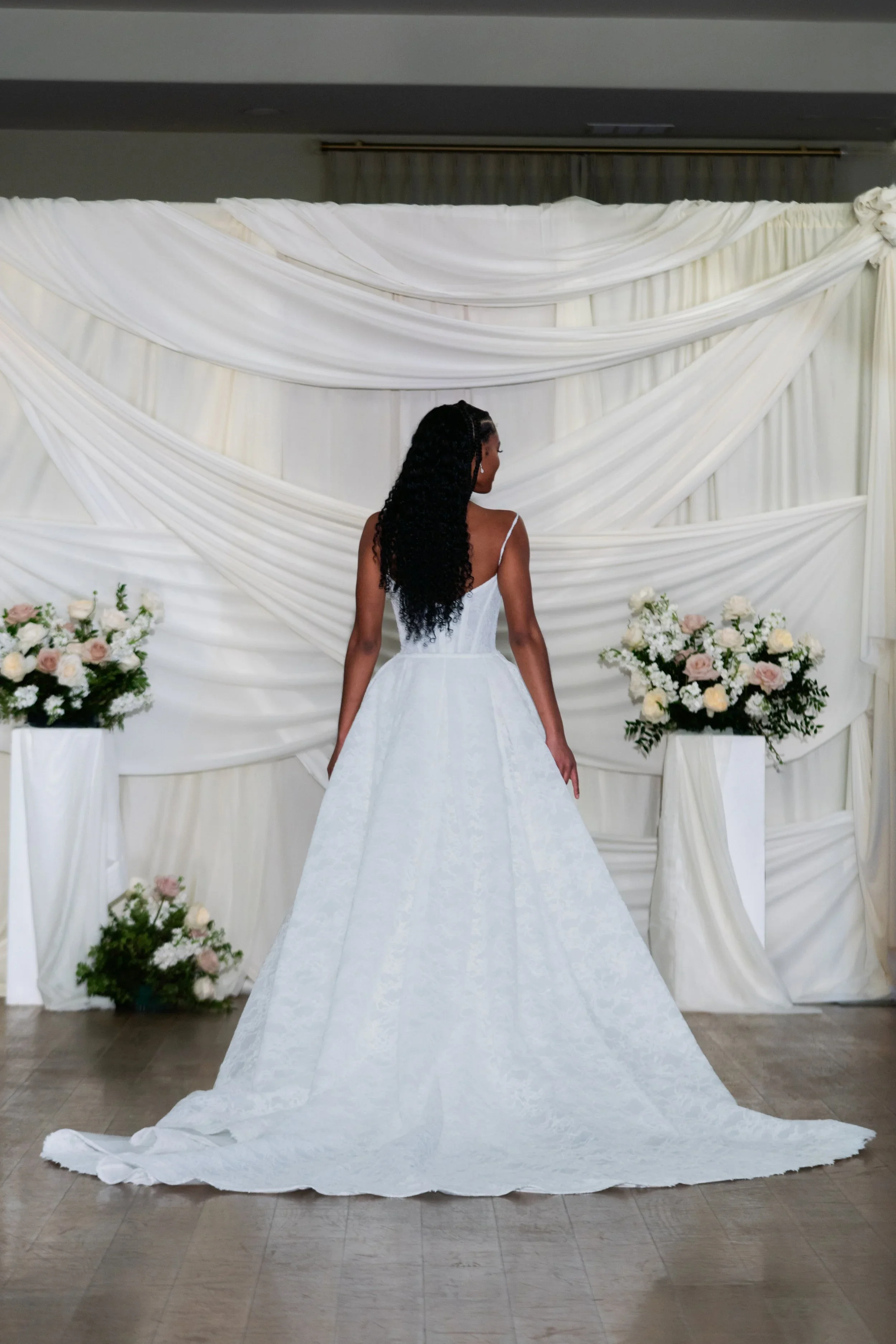 Beckett is a modern fit-and-flare gown layered with a romantic lace overskirt. A sheer corseted bodice and clean straight neckline meet a cascading lace overlay for unforgettable aisle drama.