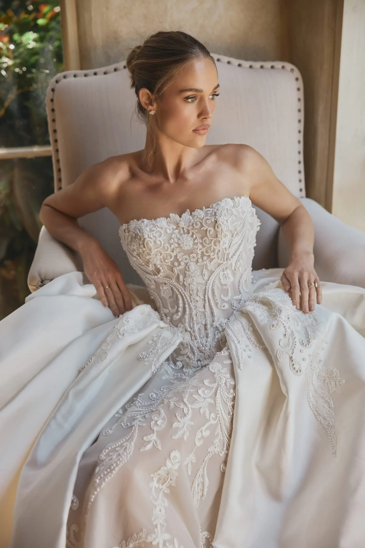 Azia by Steven Khalil couture lace wedding dress with strapless corset bodice, intricate embroidery, fitted silhouette, satin overskirt, and cathedral veil at Bride To Be Couture Sacramento