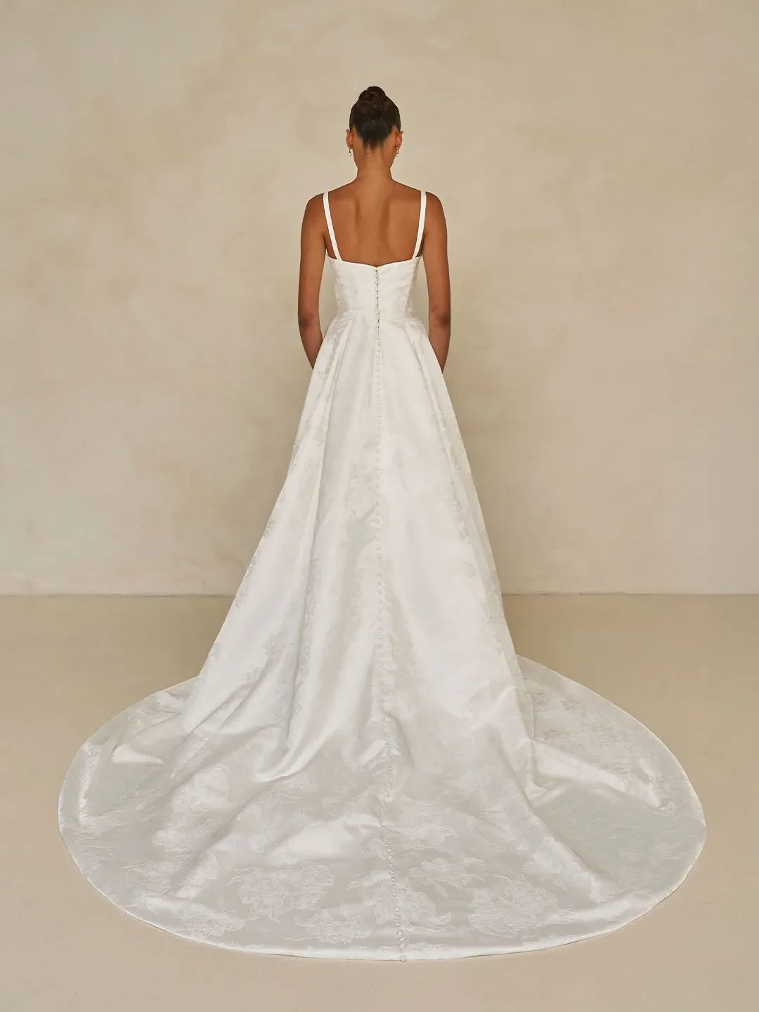 Madi Lane Walsh floral jacquard sheath wedding gown with a square neckline, detachable straps, and an included A-line overskirt for two distinct looks.