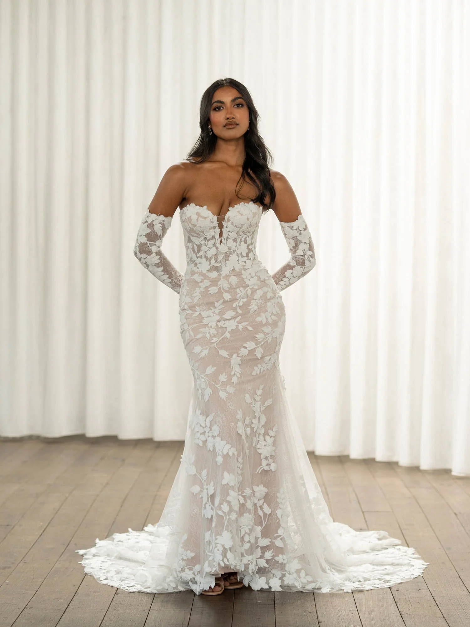 Madi Lane Thane fit-and-flare wedding gown with a plunging sweetheart illusion bodice, vine and Chantilly lace, Basque waist, and detachable long lace sleeves.