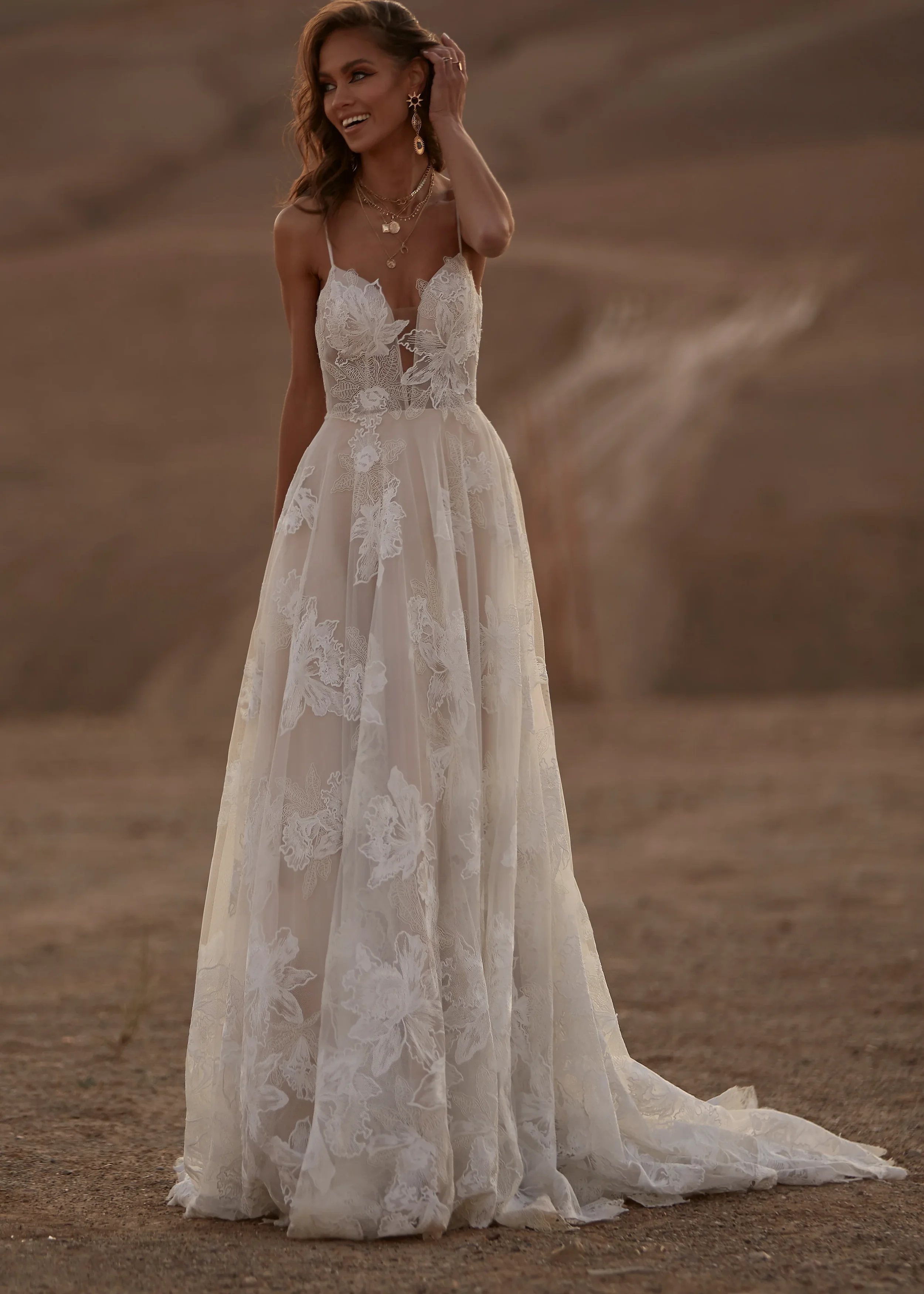 Madi Lane Avery A-line wedding dress with thin spaghetti straps, large floral lace appliqué, and a shimmering glitter tulle under-layer finished with a low circular back and pearl buttons