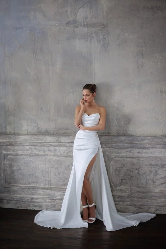 Julie Vino Brooke strapless Mikado sheath wedding dress with a sweetheart neckline, ruched bodice, and confident leg slit.