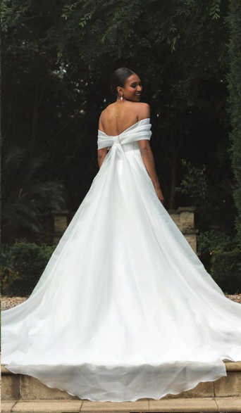 Madi Lane Prestyn A-line wedding gown in layered organza with softly pleated off-the-shoulder straps, a bow-inspired bodice, leg split, and cathedral-length train.