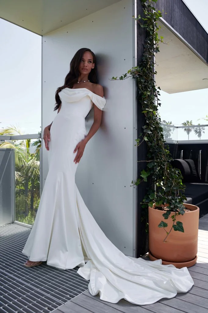 Serene Ame Altair stretch satin fit-and-flare wedding dress with off-shoulder cowl neckline, pointed waistline, and dramatic train godet.