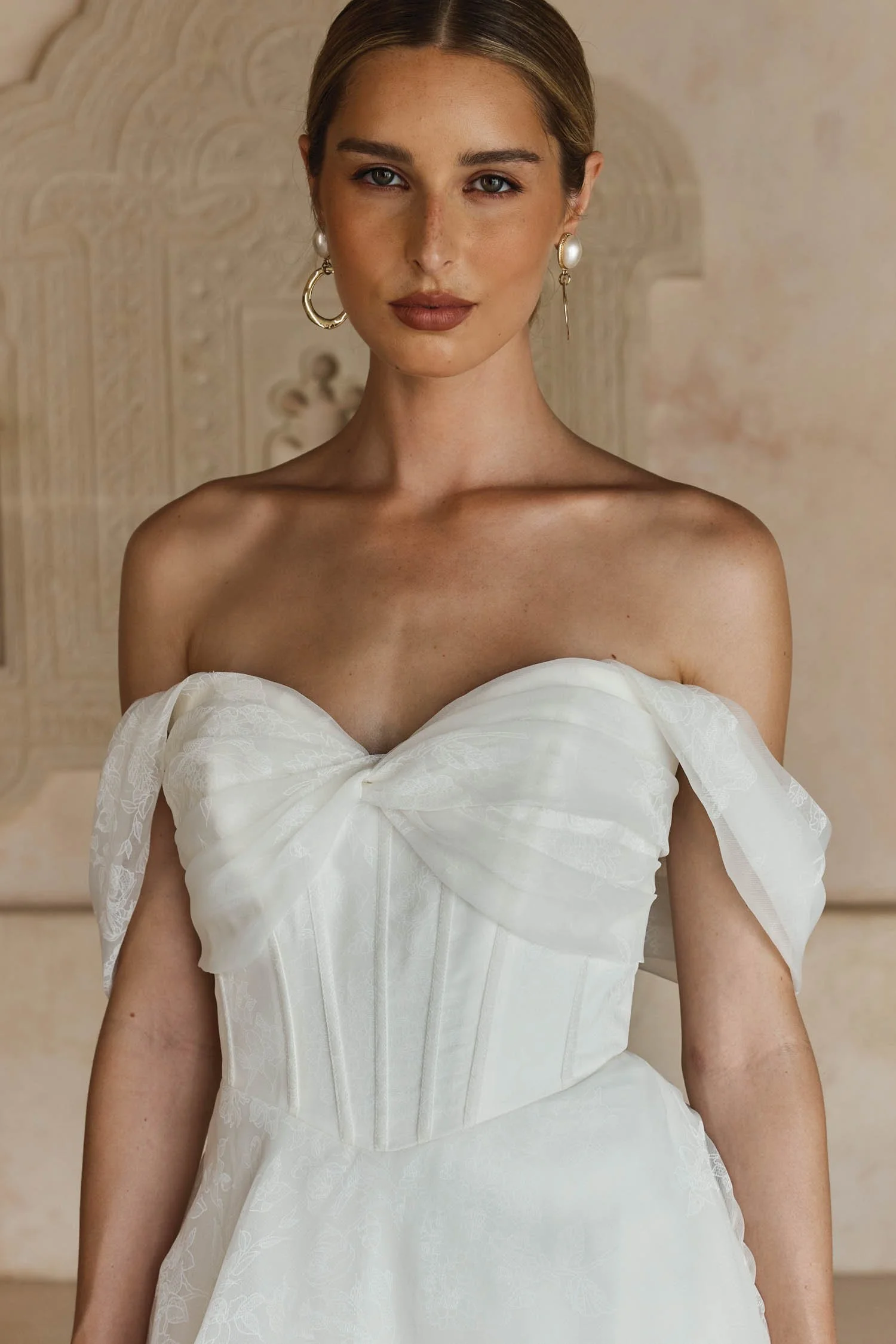 Madi Lane Lawson A-line wedding ballgown in printed floral organza with a strapless sweetheart twisted bodice, exposed corset boning, Basque waist, pockets, and detachable pleated shoulder cuffs.