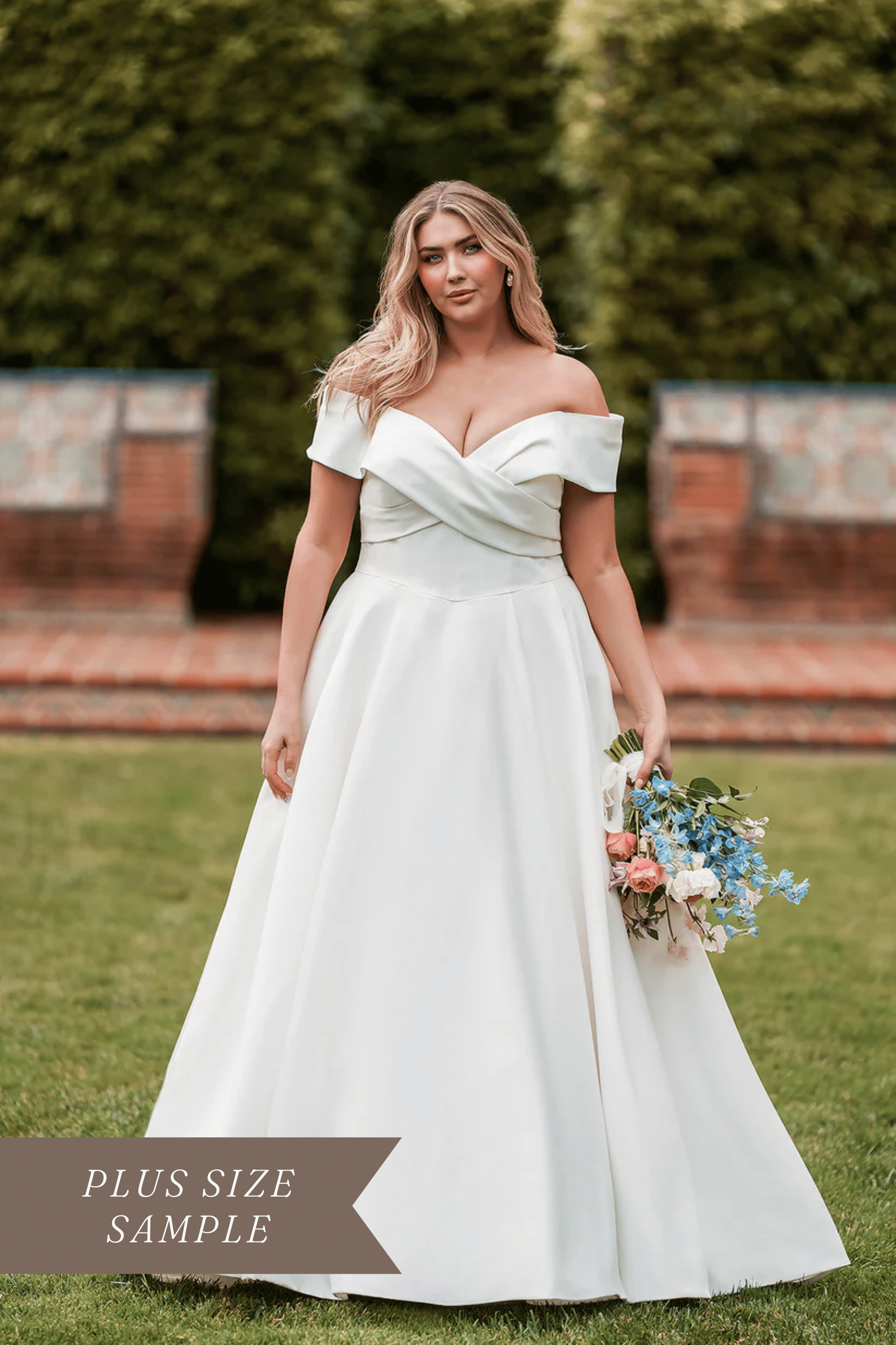 Allure Bridals W504 plus size satin ballgown wedding dress with ruched crossover bodice, off-the-shoulder sleeves, and a bow accent along the back.