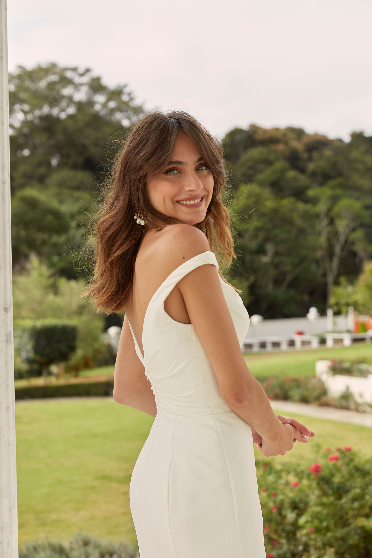 Madi Lane Darnelle minimalist crepe wedding dress with a body-hugging fit, dramatic leg split, and timeless sweeping train.