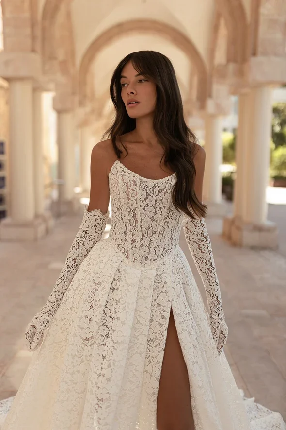 Julie Vino Catalina A-line lace wedding gown with a strapless scoop neckline, defined Basque waistline, and confident leg slit.