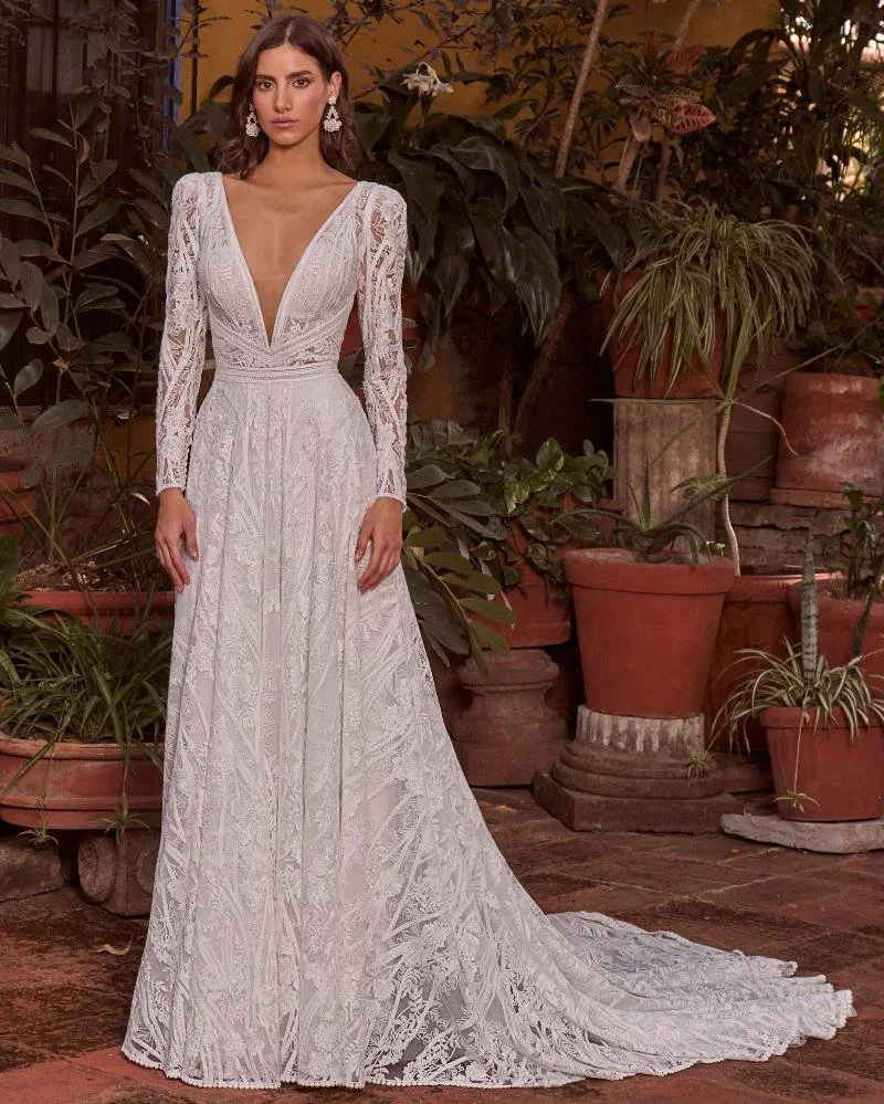 La Perle Kya boho lace A-line wedding dress with deep V-plunge neckline, detachable long sleeves, tank straps, and long train.