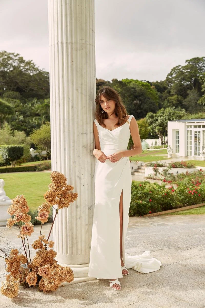 Madi Lane Darnelle minimalist crepe wedding dress with a body-hugging fit, dramatic leg split, and timeless sweeping train.