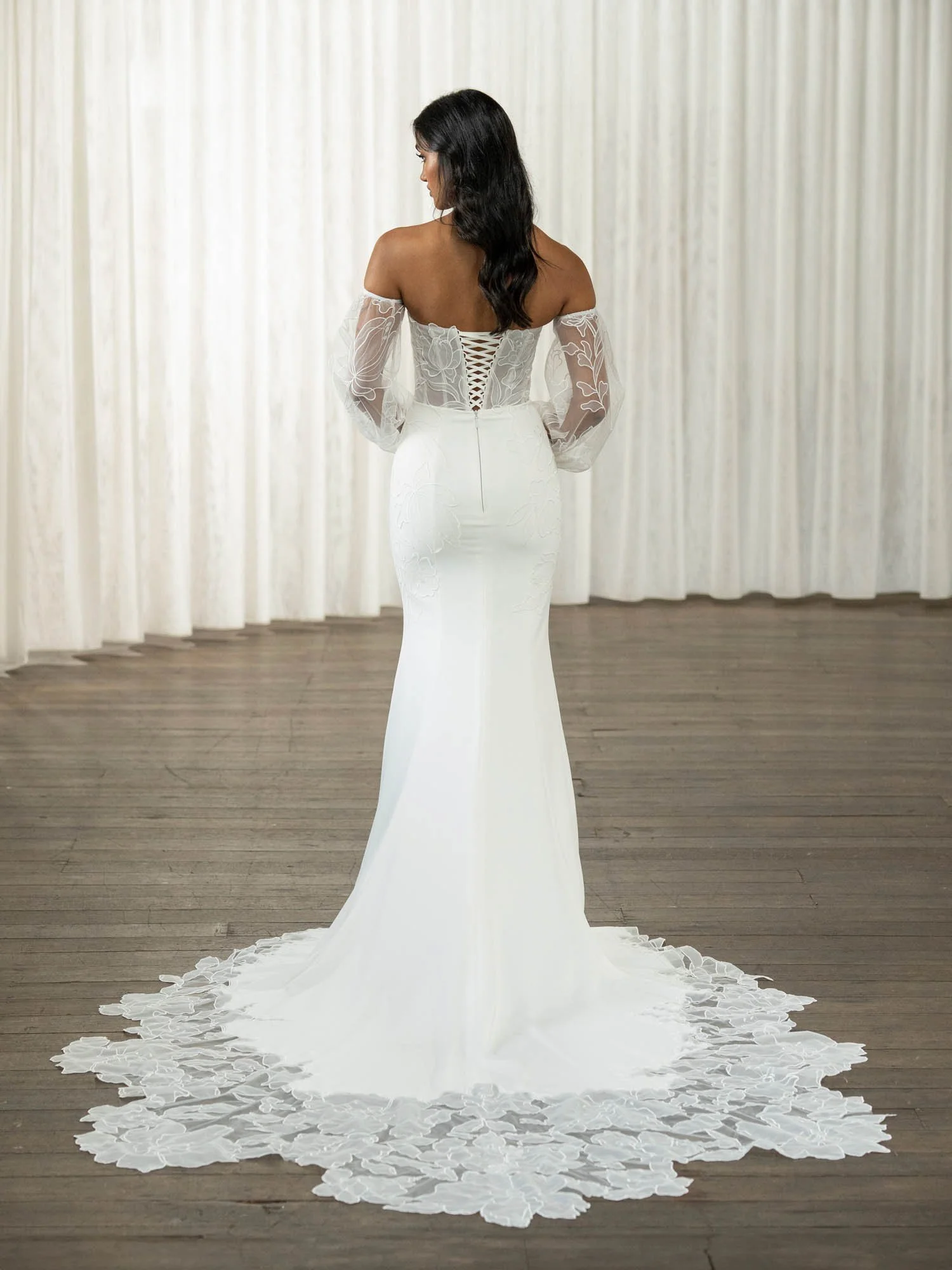 Madi Lane Tamra fit-and-flare crepe wedding dress with a scoop illusion bodice, abstract floral embroidery, detachable long lace sleeves, and a statement Watteau train.