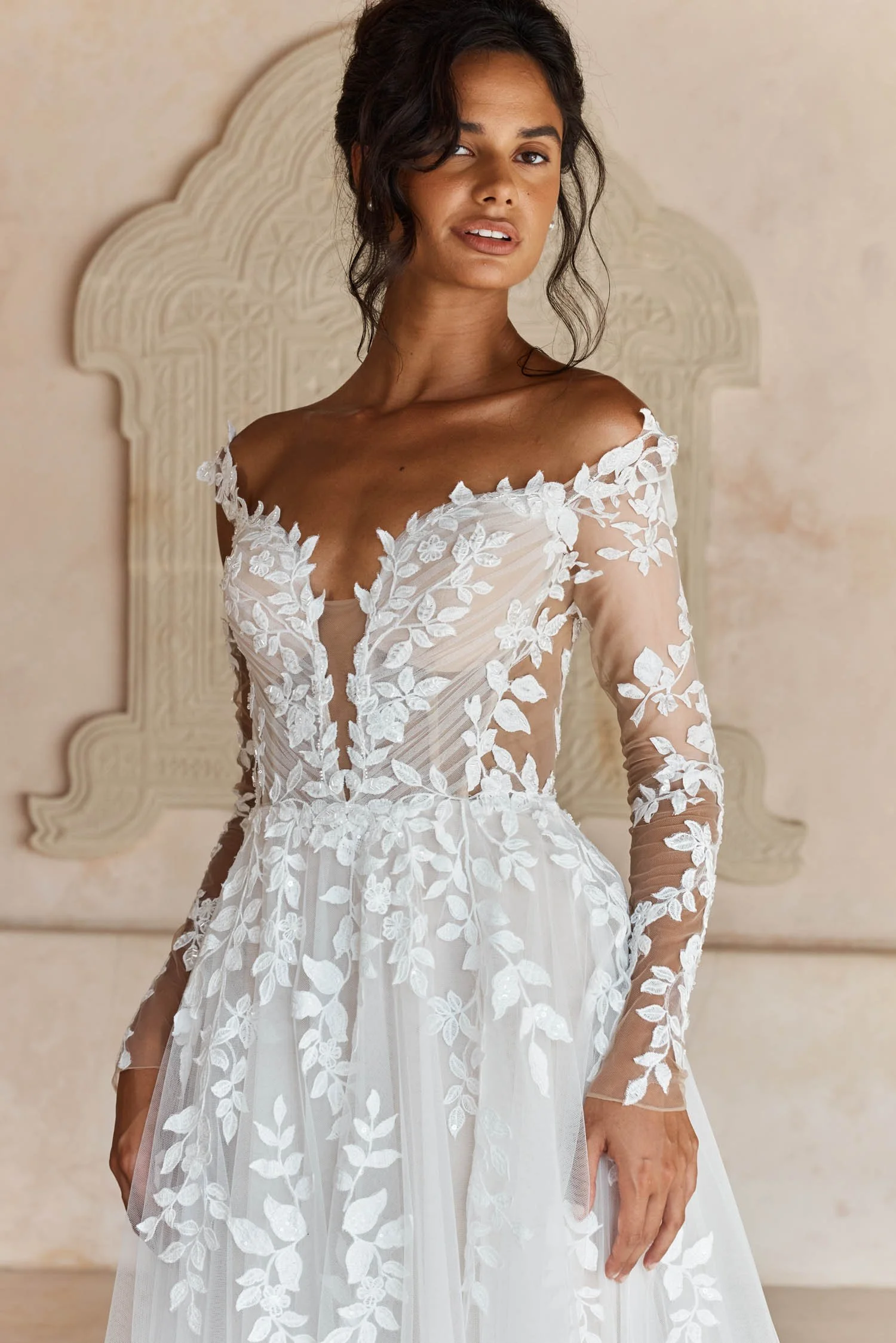 Madi Lane Landon A-line wedding dress with a pleated tulle illusion bodice, embroidered lace motif straps, detachable fitted long lace sleeves, and a floaty lace-cut hem.