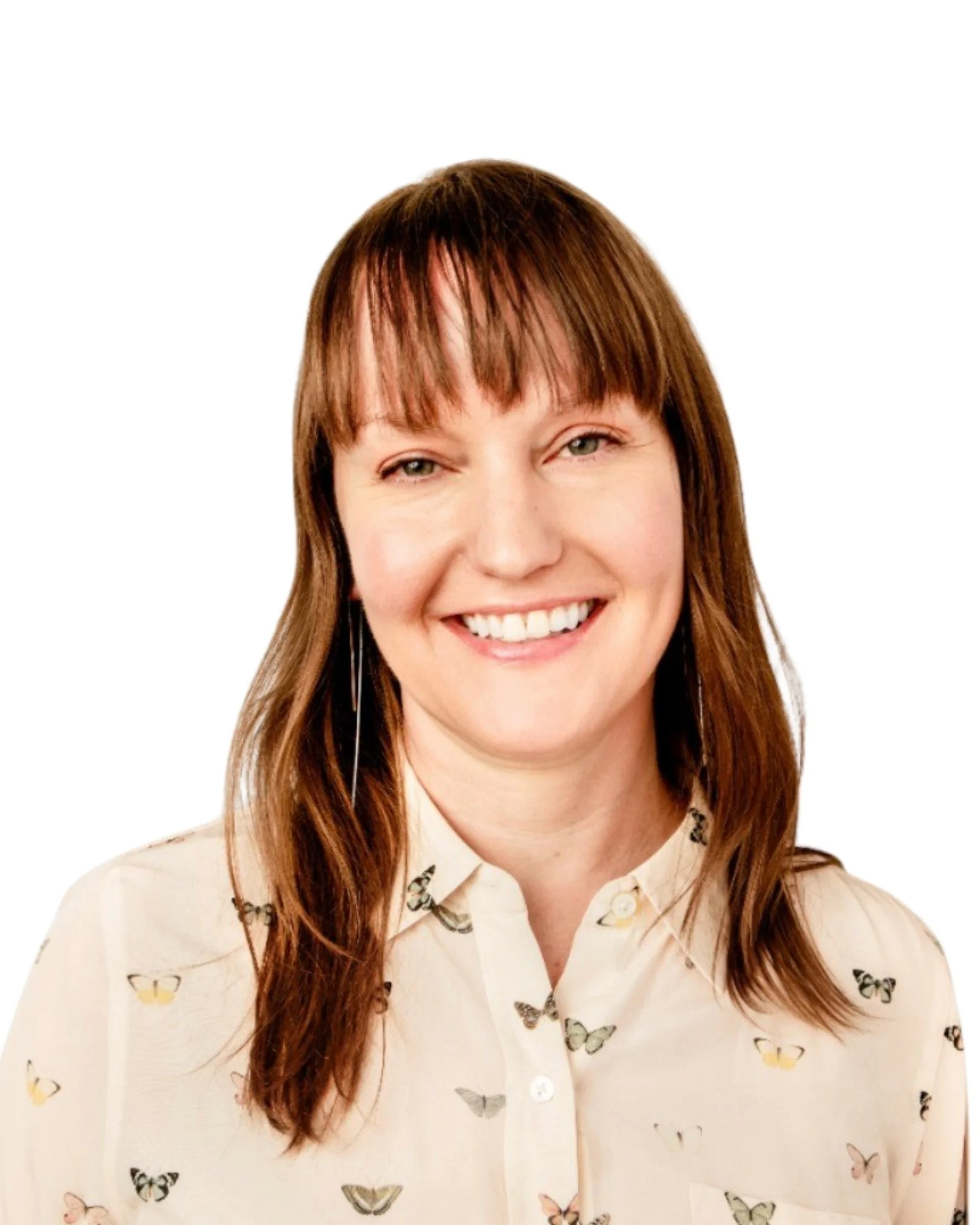 A woman with shoulder-length brown hair and bangs, smiling, wearing a cream-colored blouse with butterfly prints.