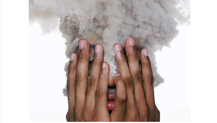 a person covering their face with their hands with smo