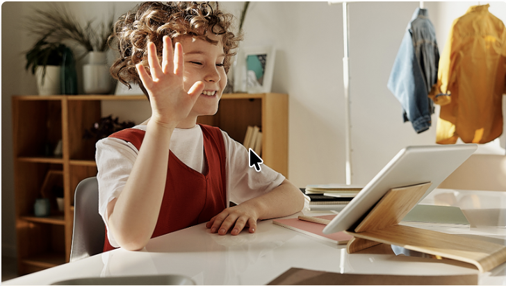 a child raising their hand in front of a laptop