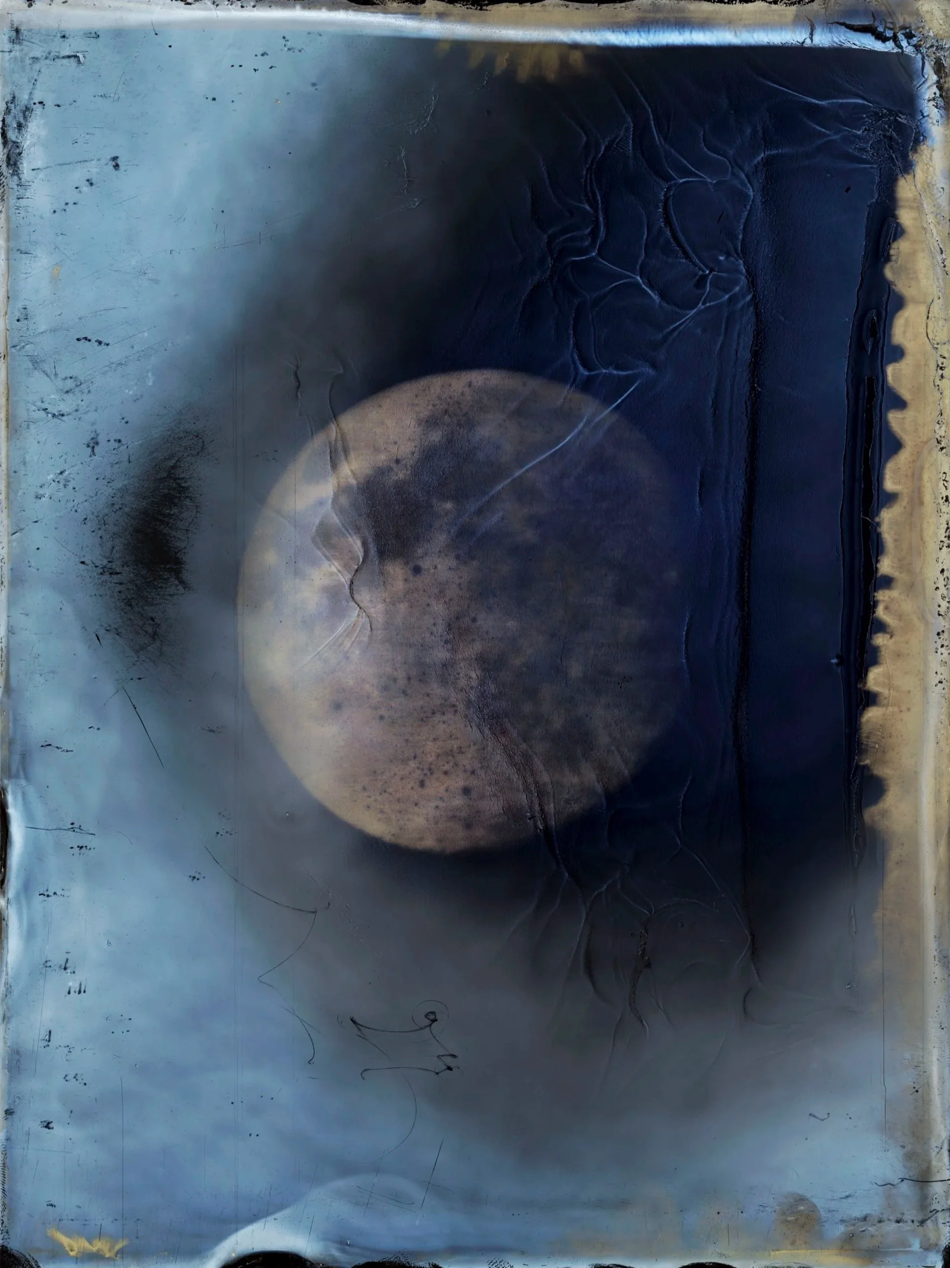 Close-up of a metallic surface with a circular, moon-like object and black, crackled paint or corrosion around it.