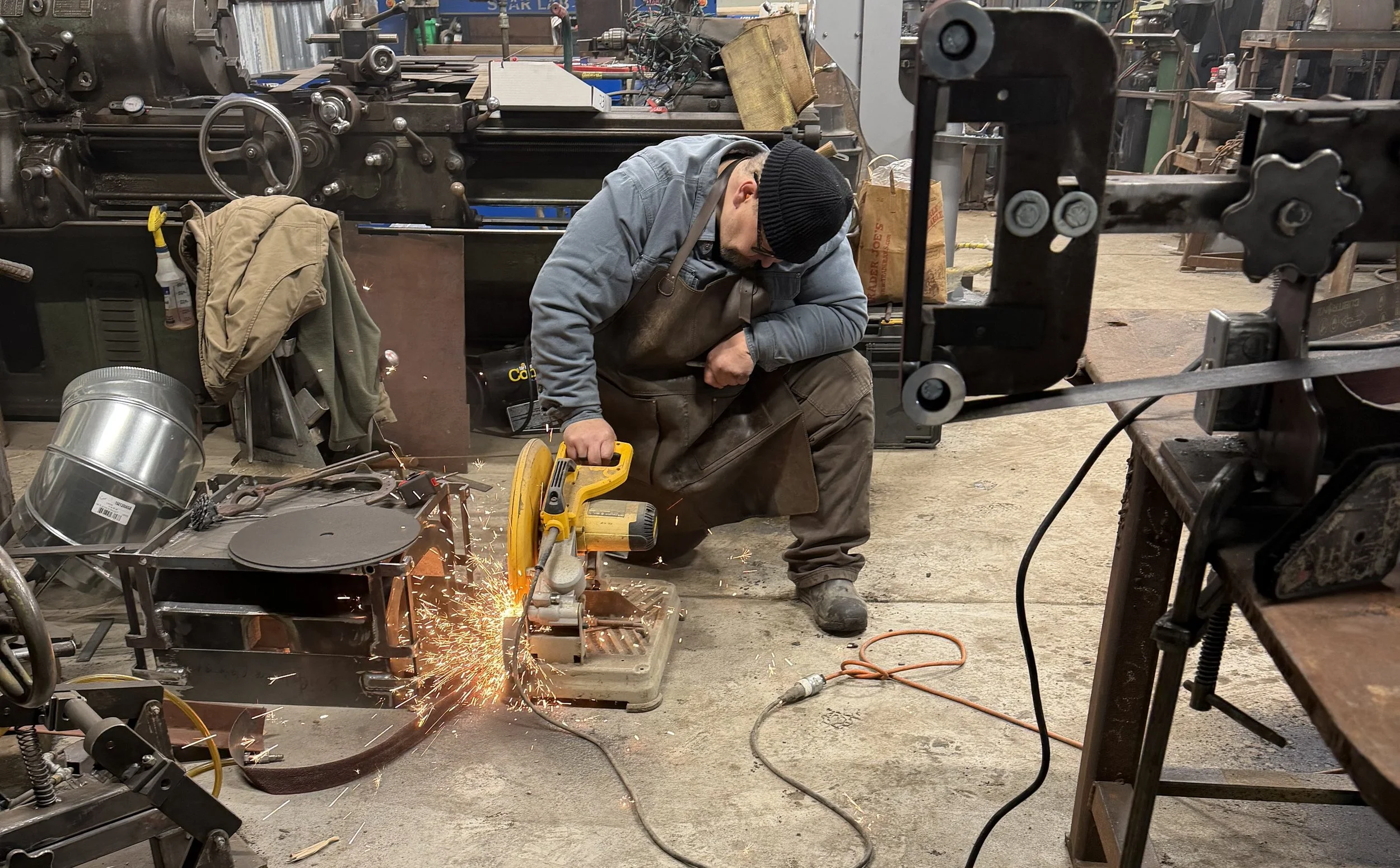 Zeke Ziegler cutting a Damascus billet during a Guild of Metalsmith Class in 2026