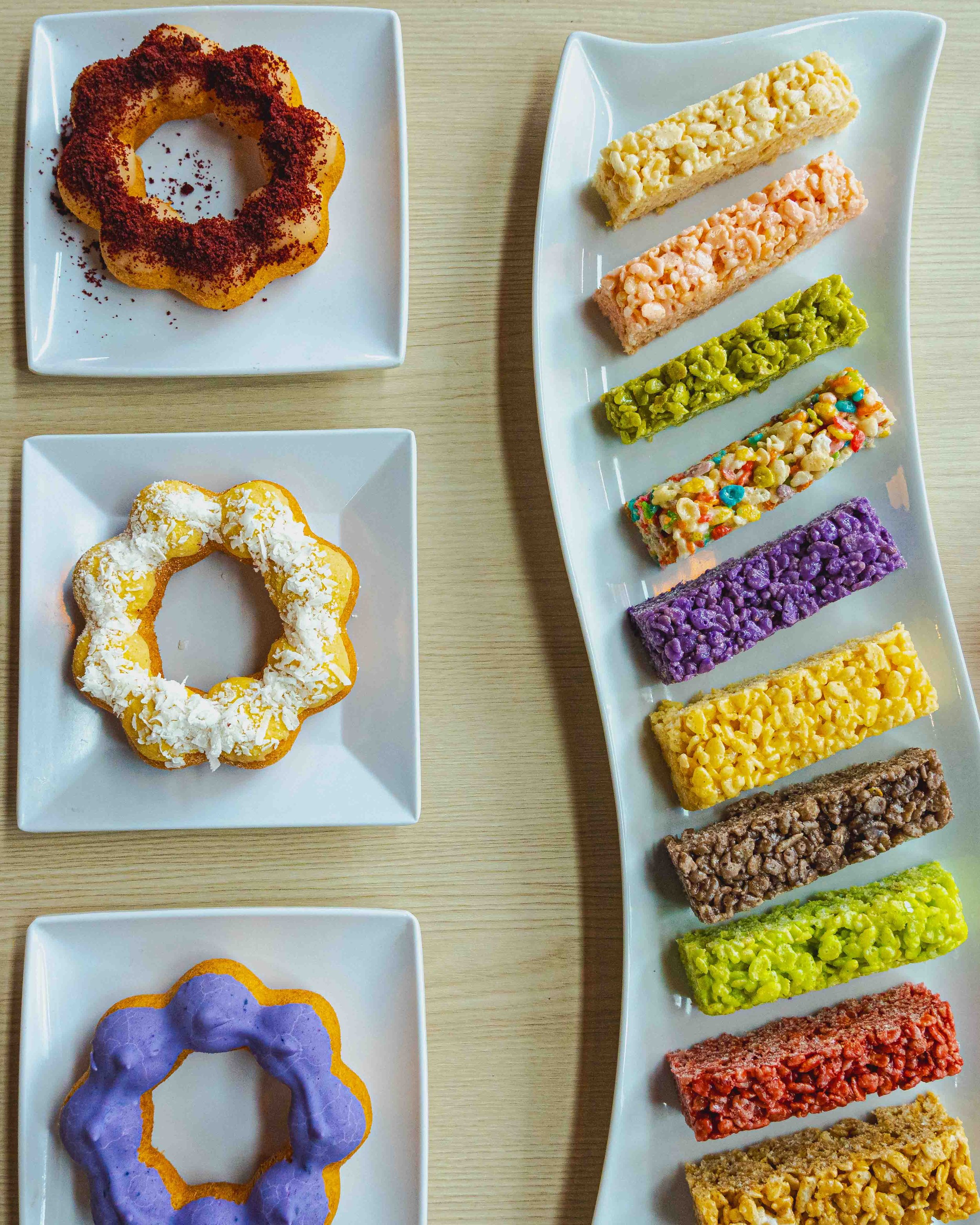 Decorative cookies and rice crispy treats on white rectangular and square plates.