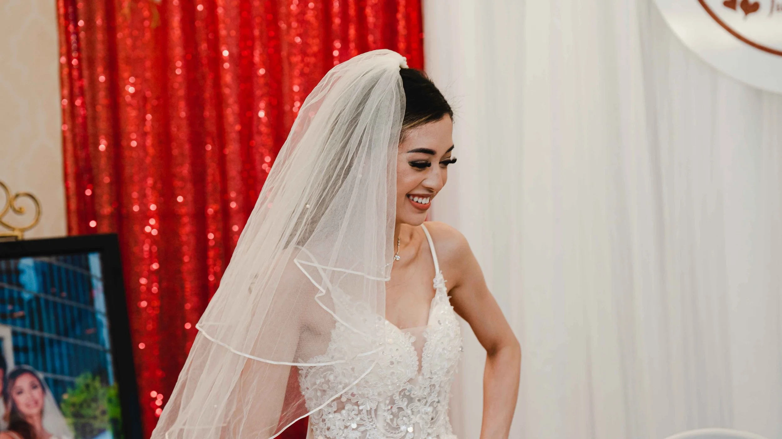 A woman in a wedding dress and veil smiling as she prepares for her wedding.