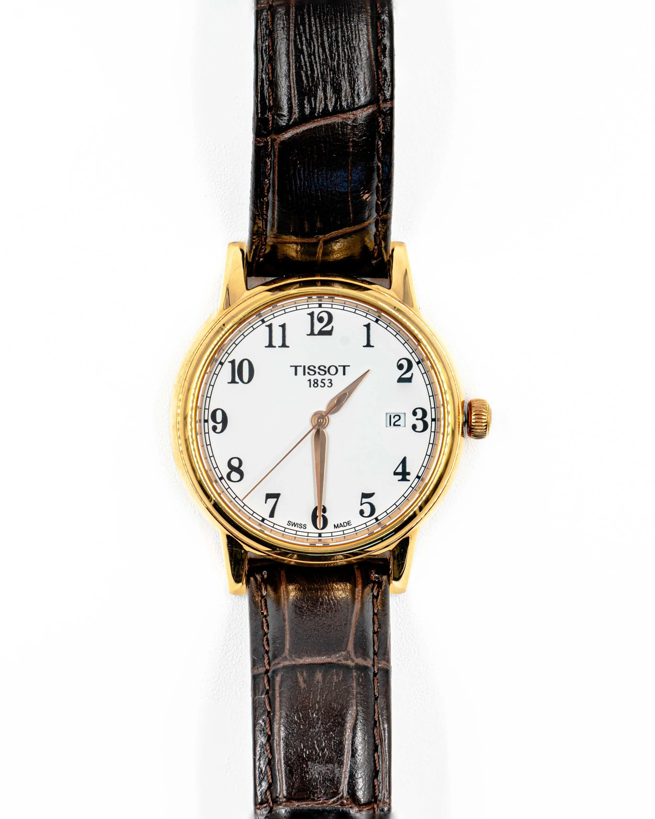 Close-up of a gold Tissot wristwatch with a white dial and black leather strap.