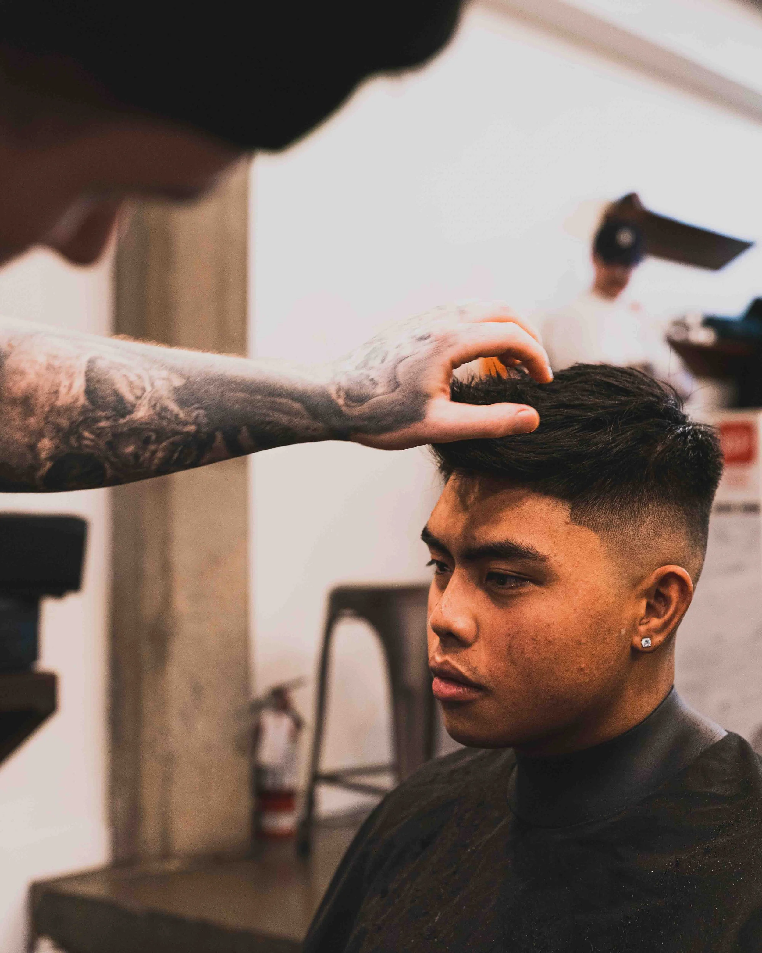 A barber cutting a man's hair with a pair of scissors in a salon.