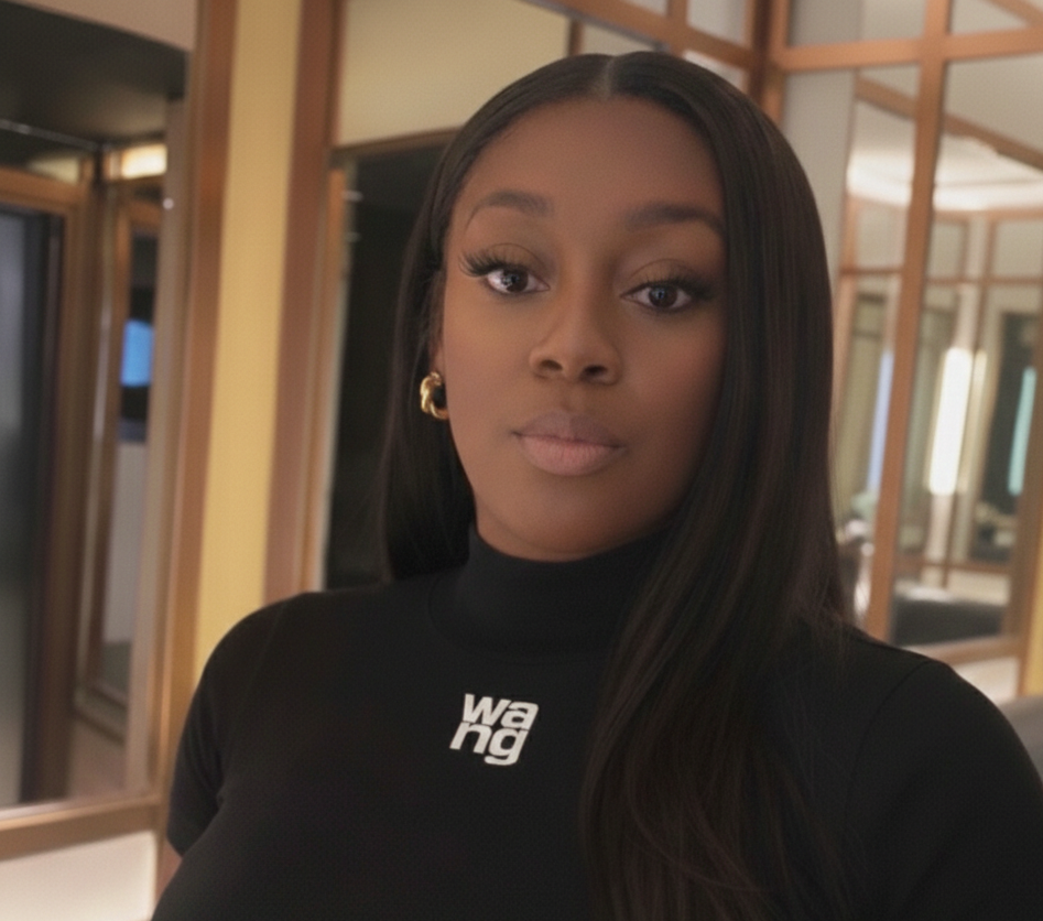A woman with long dark hair and gold earrings taking a selfie inside a room with mirrors and wooden frames.