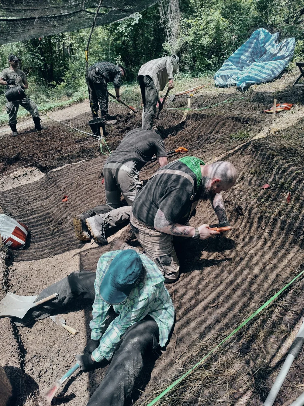 Team members excavating at a field recovery dig site