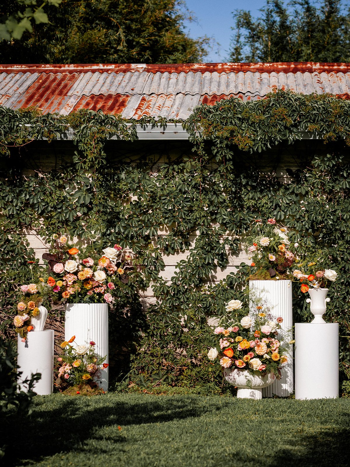 Wedding ceremony summer florals orange yellow on plinths.jpg