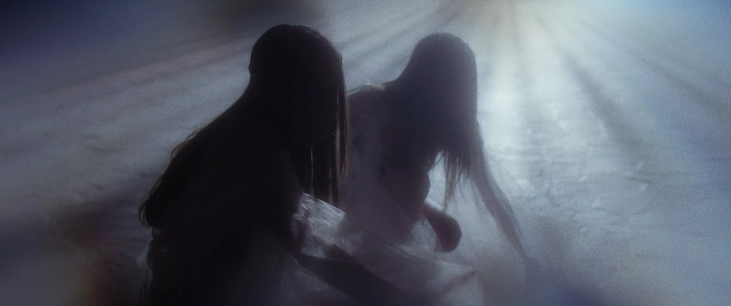 Silhouettes of three women sitting together in a foggy environment with bright light shining from behind.