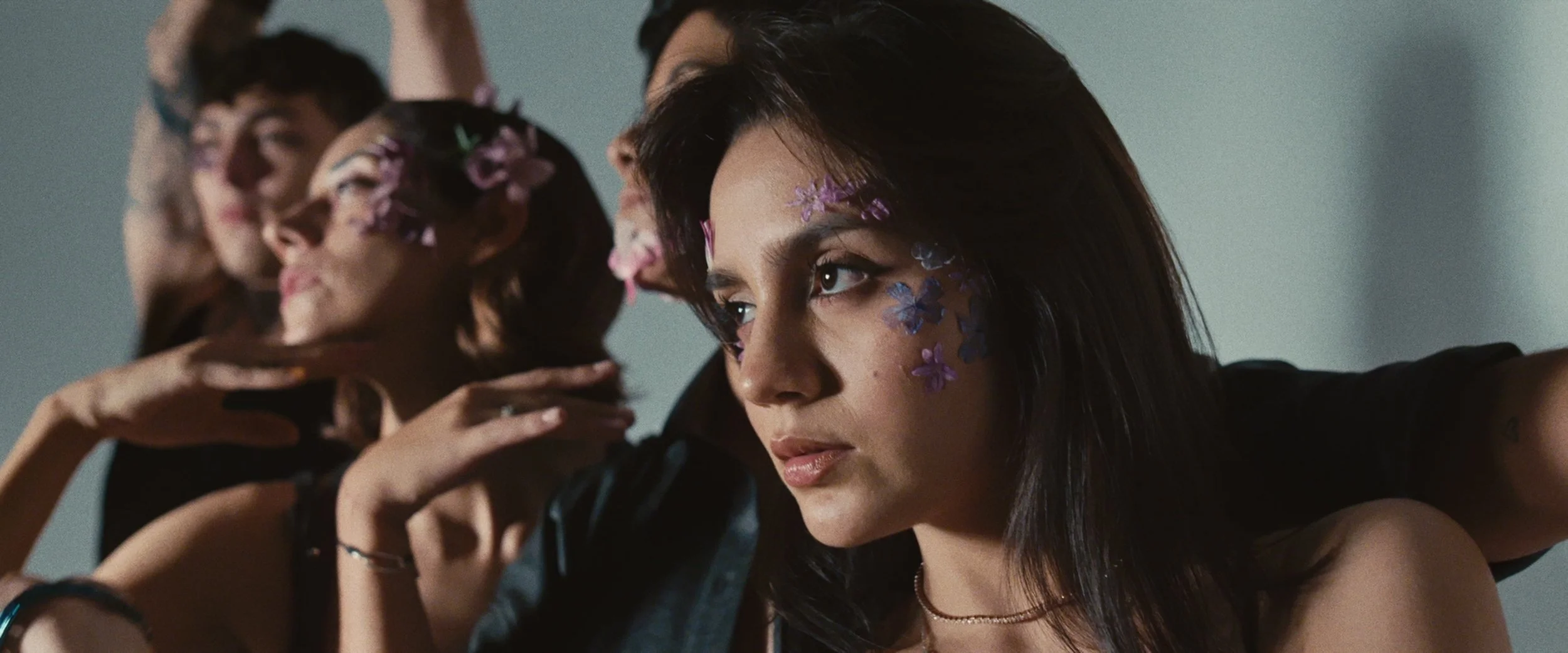 A group of young women with flower face paint, posing for a photo with serious expressions.