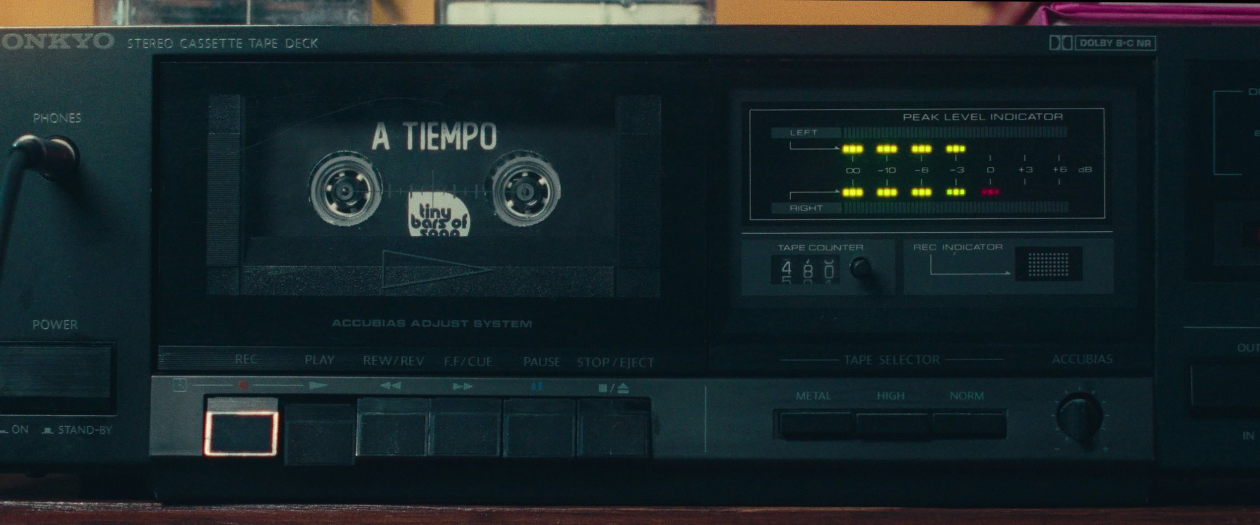 A vintage Sony stereo cassette tape deck with a cassette tape labeled "A Tiempo" inside. The deck has various controls, display indicators, and a peak level indicator showing audio levels.