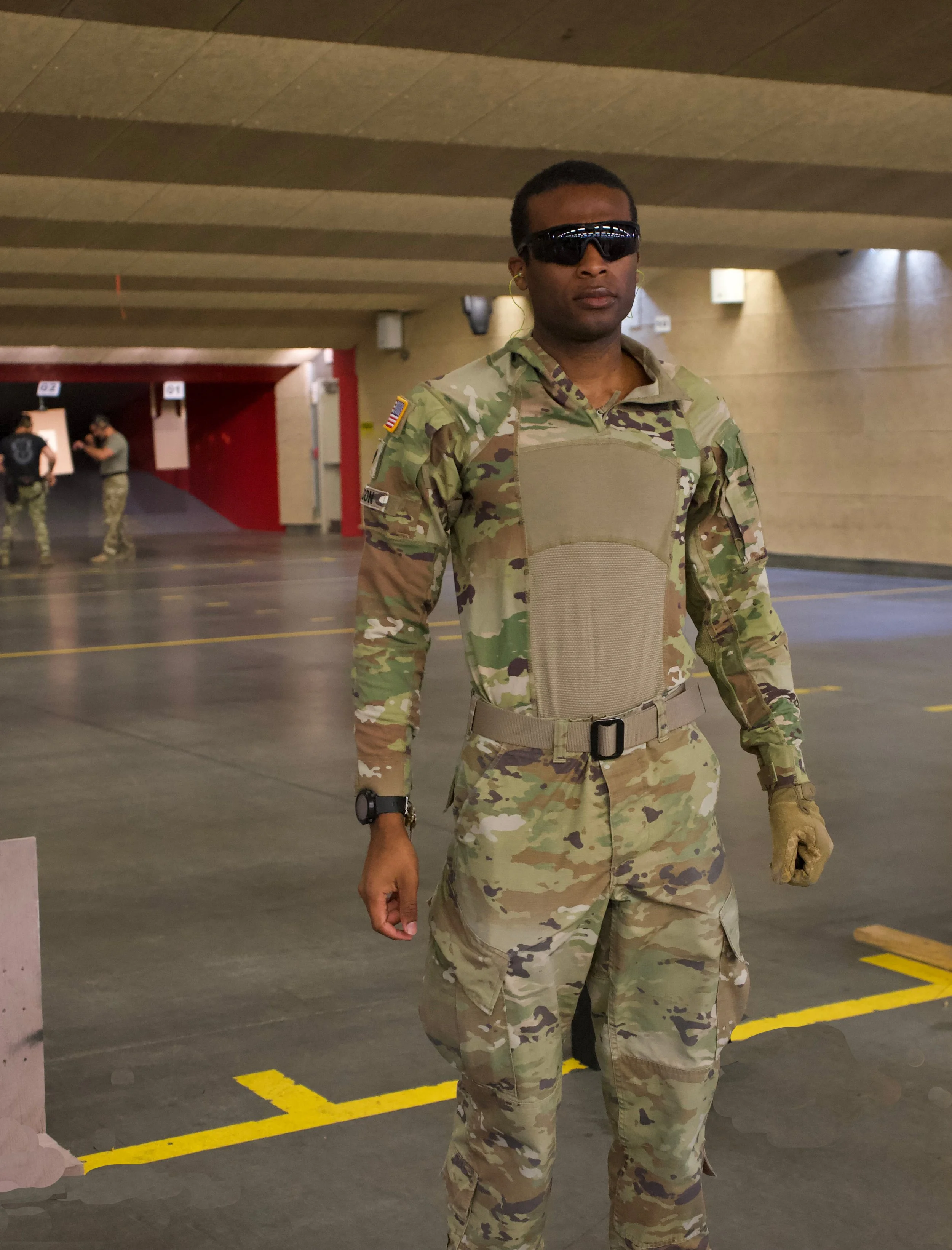 Roger Jackson  wearing tactical gear, sunglasses, and gloves standing in an indoor parking garage.