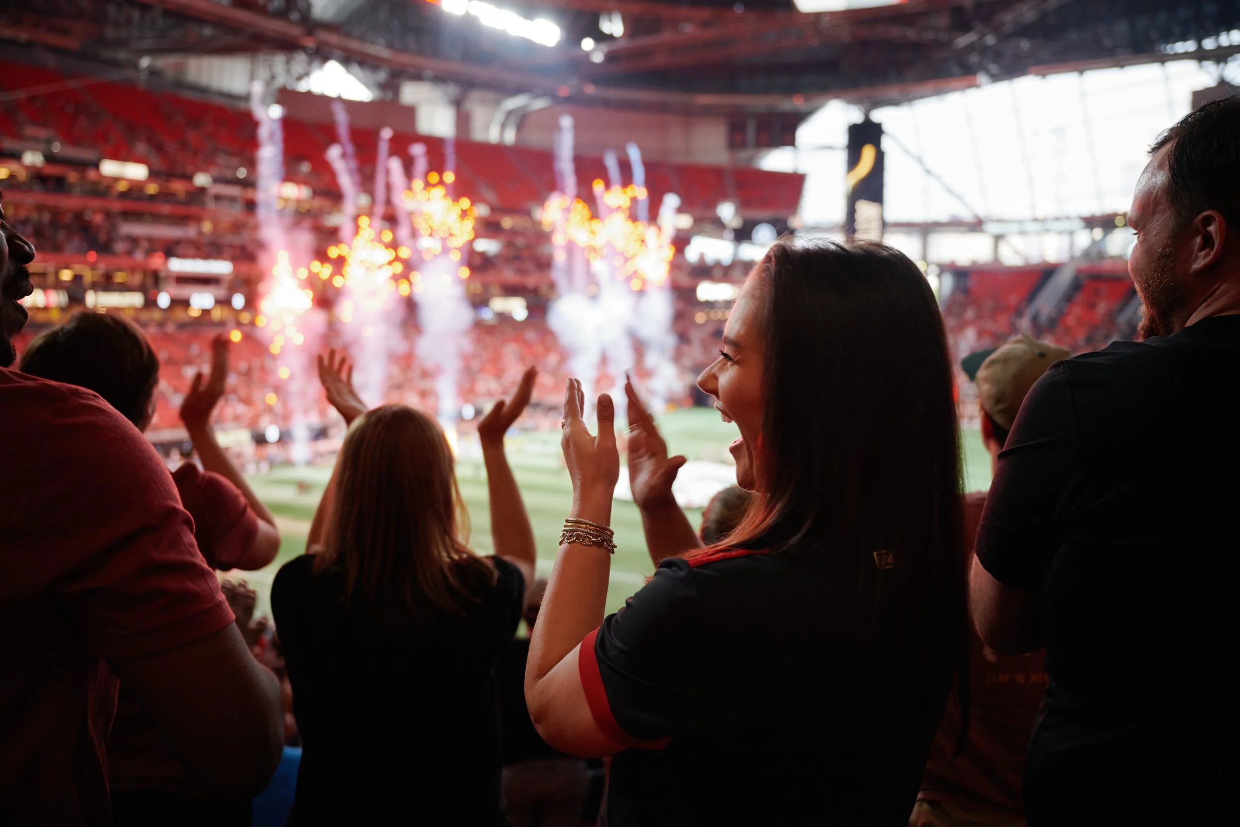 People watching a sports event in a stadium with fireworks and bright lights in the background. Soccer experience. 