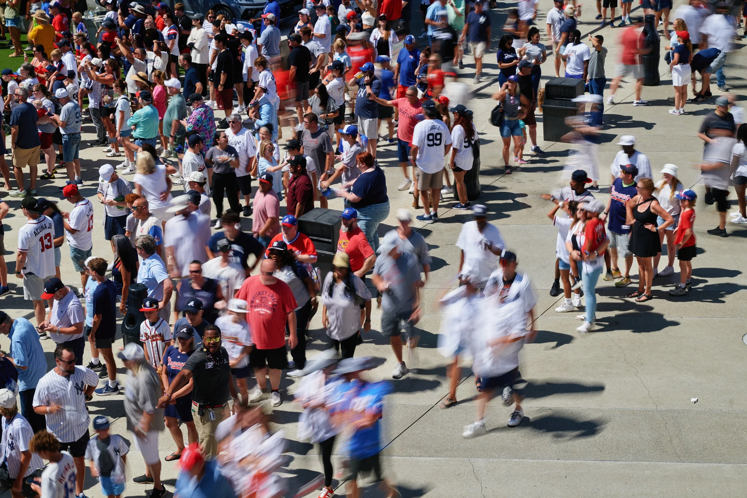 Crowd of people wearing Atlanta Braves baseball jerseys and hats at an outdoor event. Sports photography. 