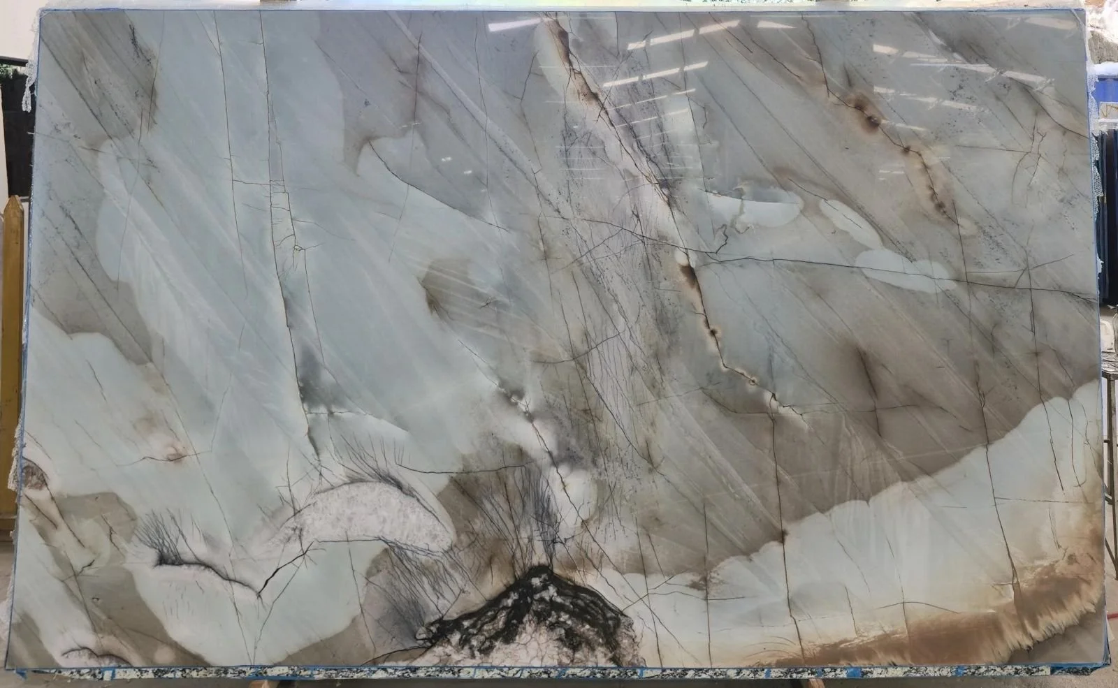 A large slab of polished marble with swirling patterns in shades of gray, white, and beige, featuring natural veining and mineral inclusions.