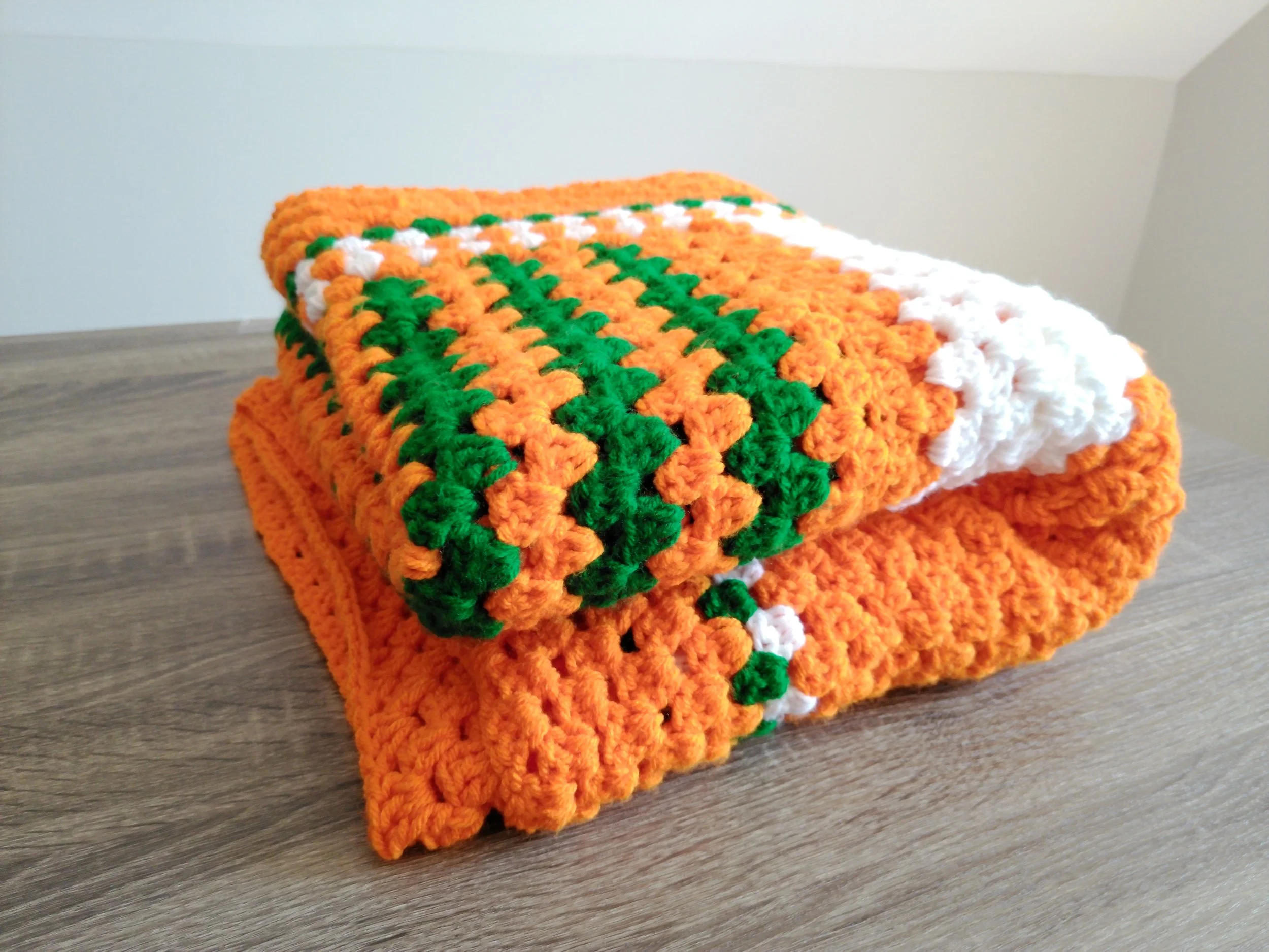 Orange Green and White blanket Folded on table.JPG