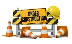 Construction site with orange traffic cones, a yellow hard hat, and an