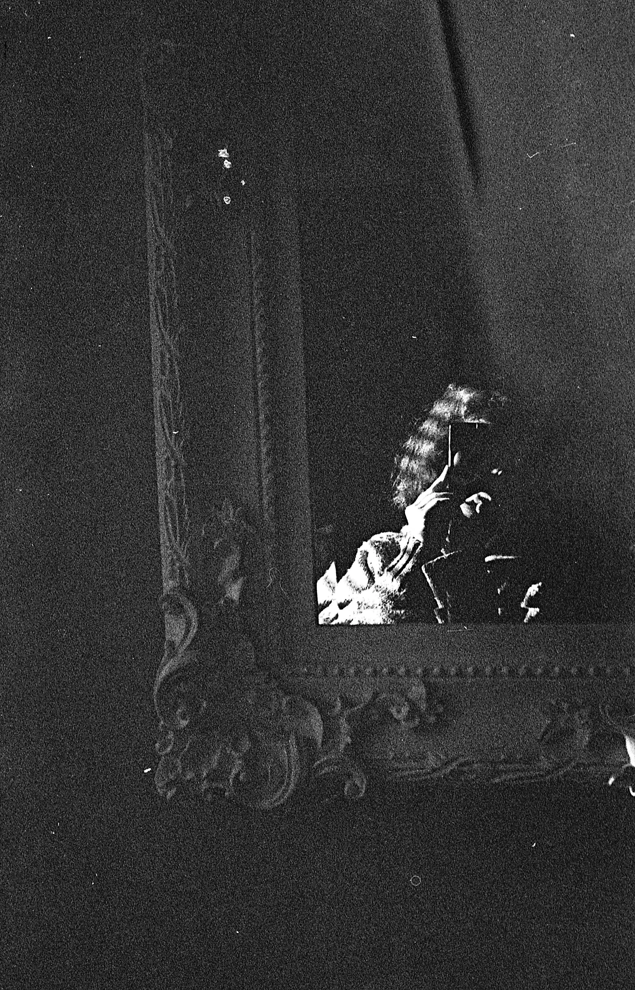 A woman with curly hair taking a selfie in a mirror with a vintage ornate frame