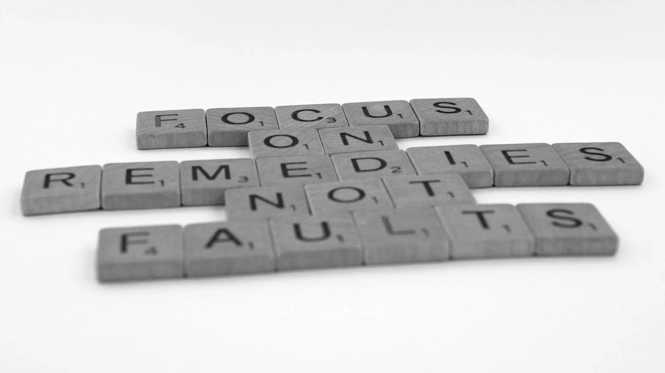 Scrabble tiles spelling out the words 'focus on remedies not faults'.