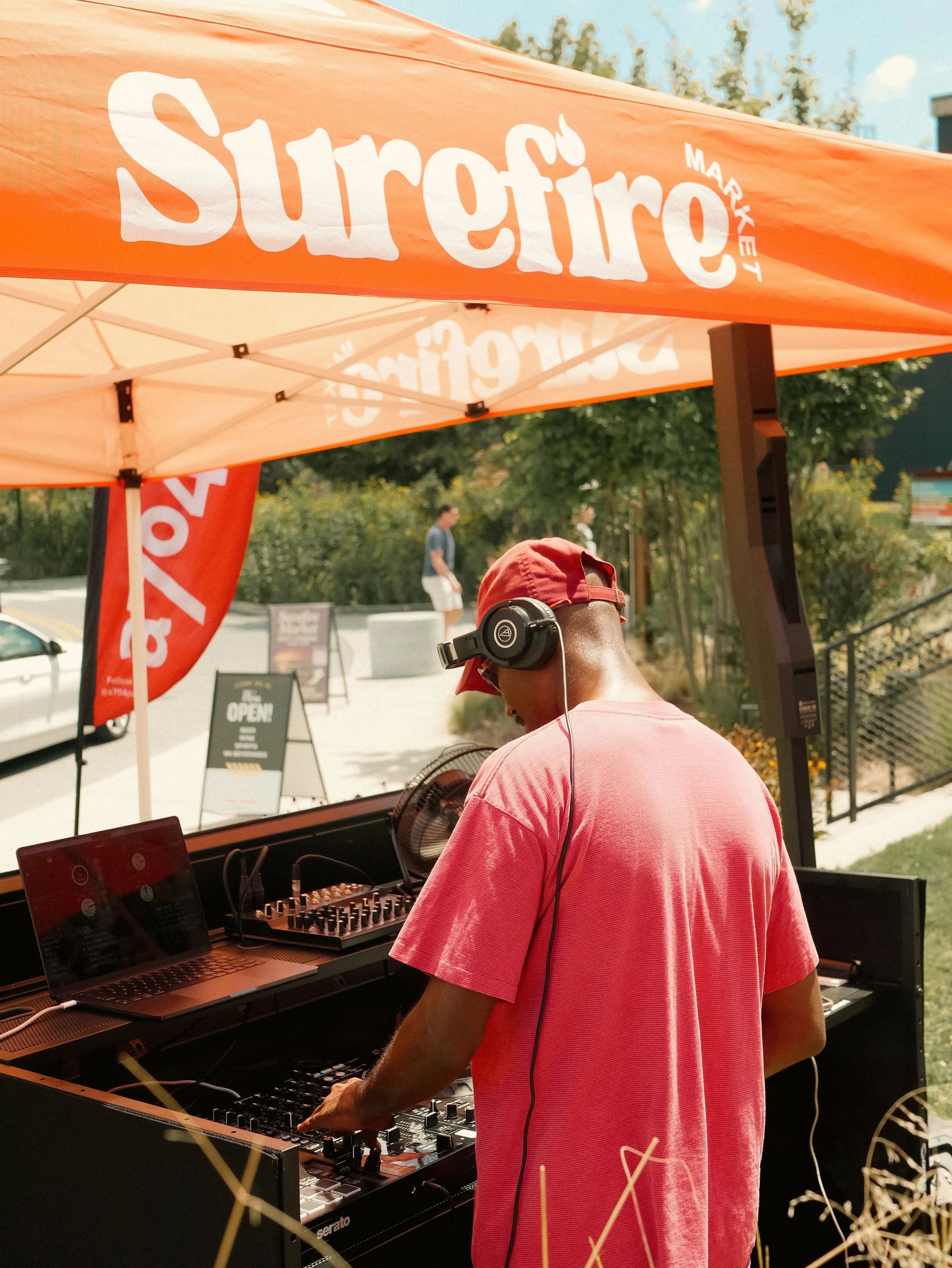 A man DJing at an outdoor event under an orange tent with 
