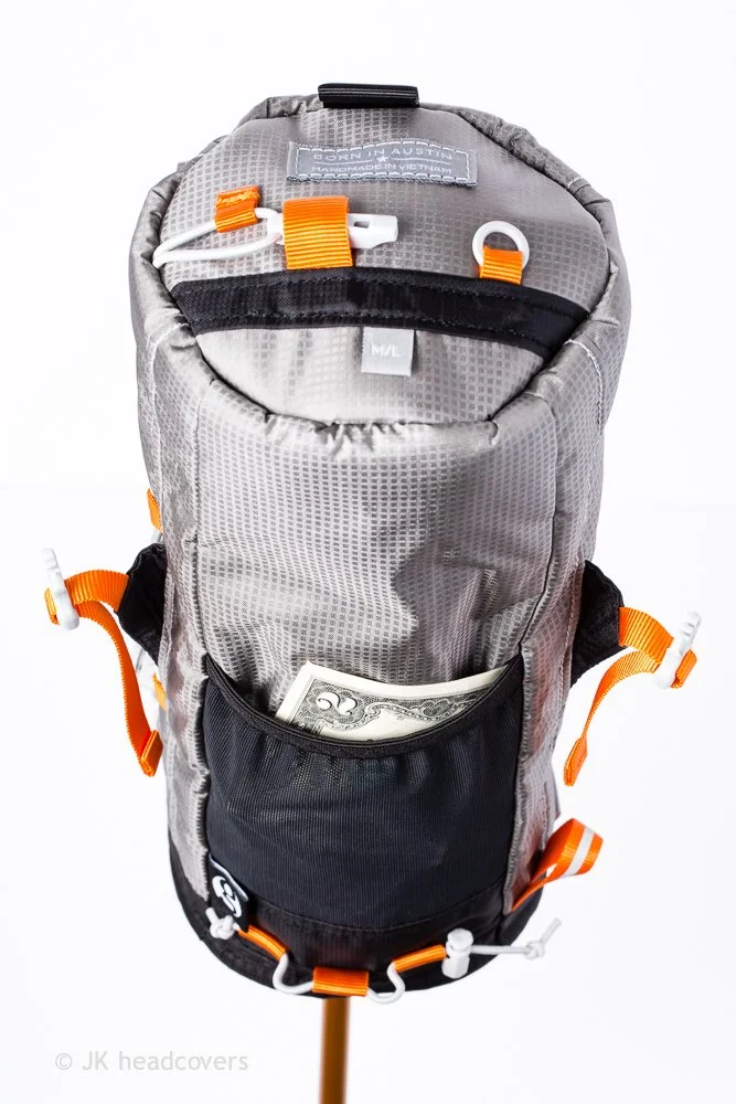 A gray and black hiking backpack with orange straps, featuring a front pocket with a two-dollar bill sticking out, on a white background.