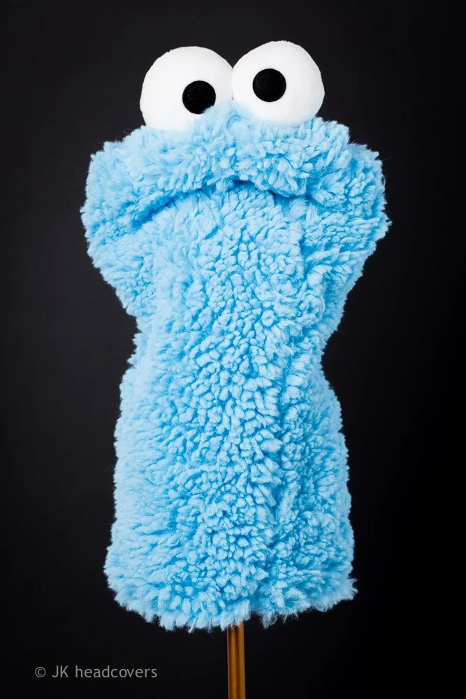 Felt puppet resembling Cookie Monster from Sesame Street with big googly eyes and fluffy blue body on a stick.