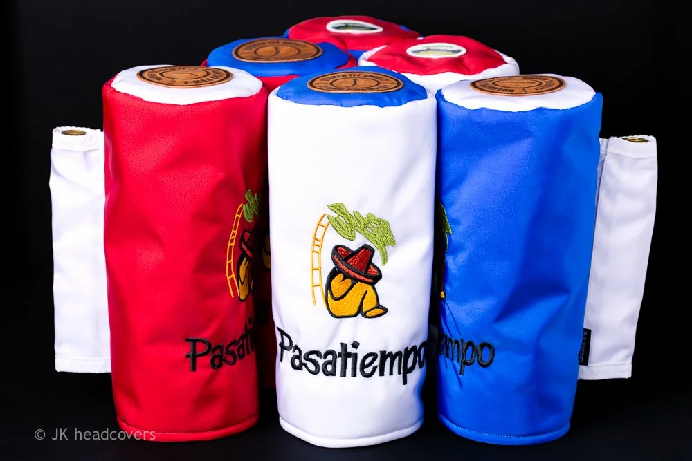 Colorful fabric rolls with embroidery and a logo, featuring red, white, and blue sections, on a black background.