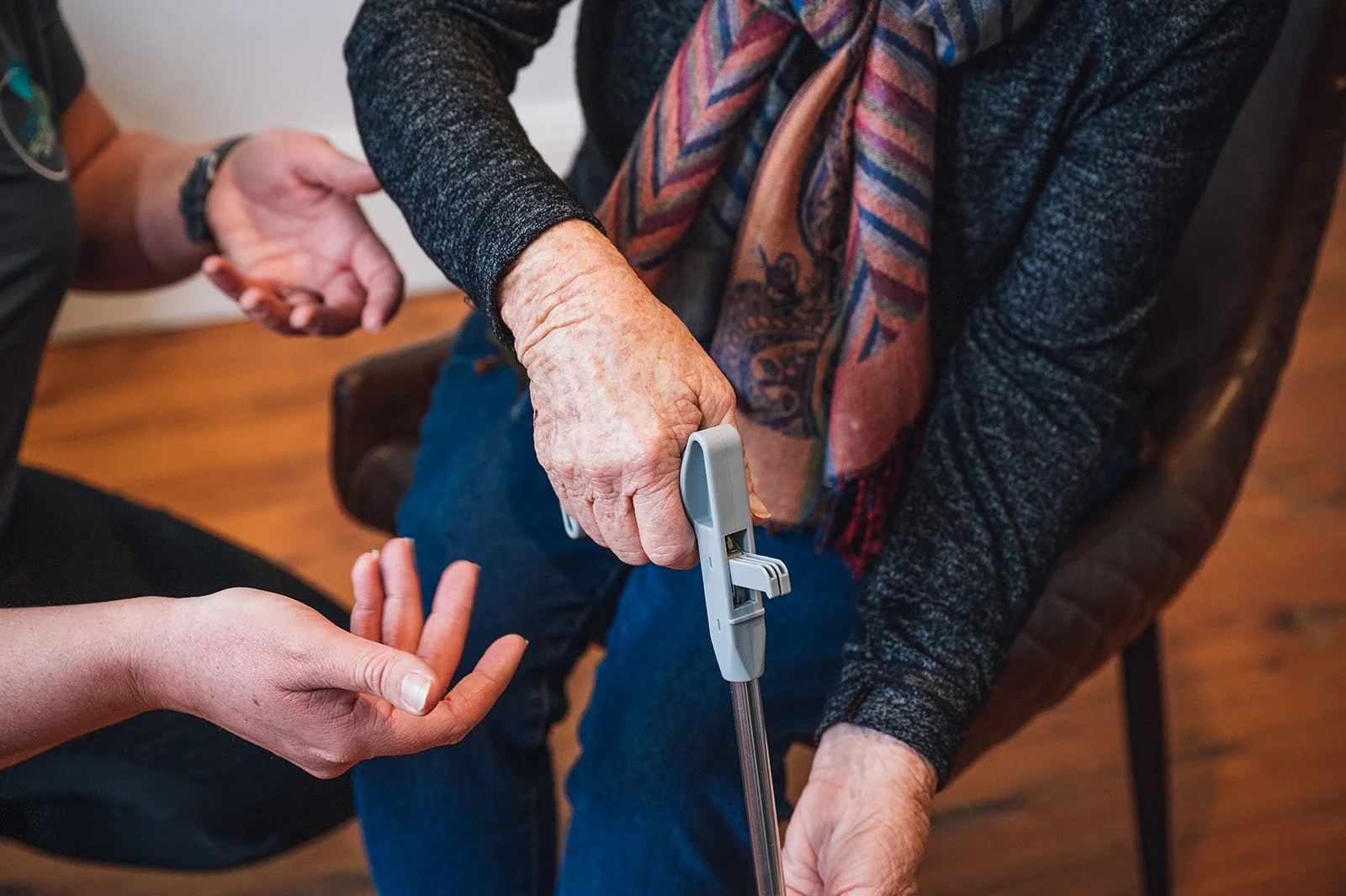 photo of occupational therapist showing a senior person how to use an aid. Total Health Orange