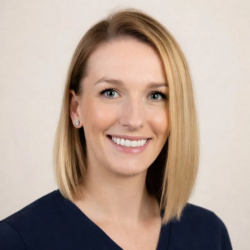 A smiling woman with shoulder-length blonde hair, blue eyes, wearing earrings and a black top.