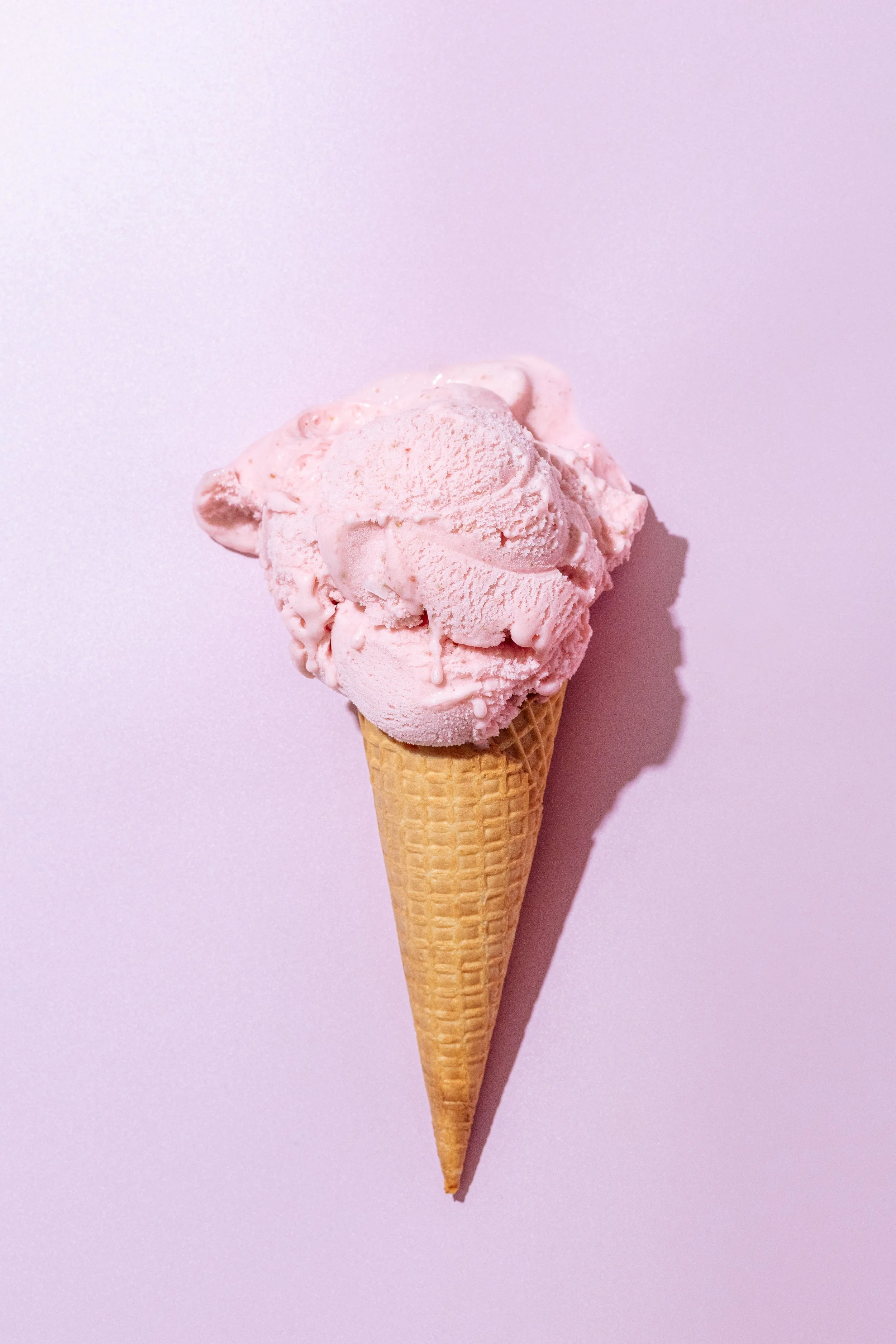 A scoop of Future Swirl strawberry in a waffle cone