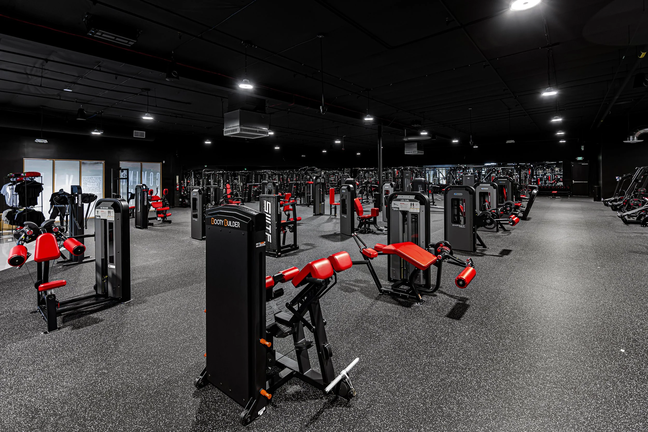Empty gym showcasing premium exercise machines, strength training equipment, speckled rubber flooring, and black ceiling lighting at Self Made Training Facility Temecula Valley—highlighting a 24/7 high-performance training environment.