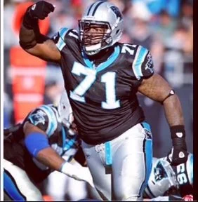 American football player in black and blue uniform making a gesture on the field