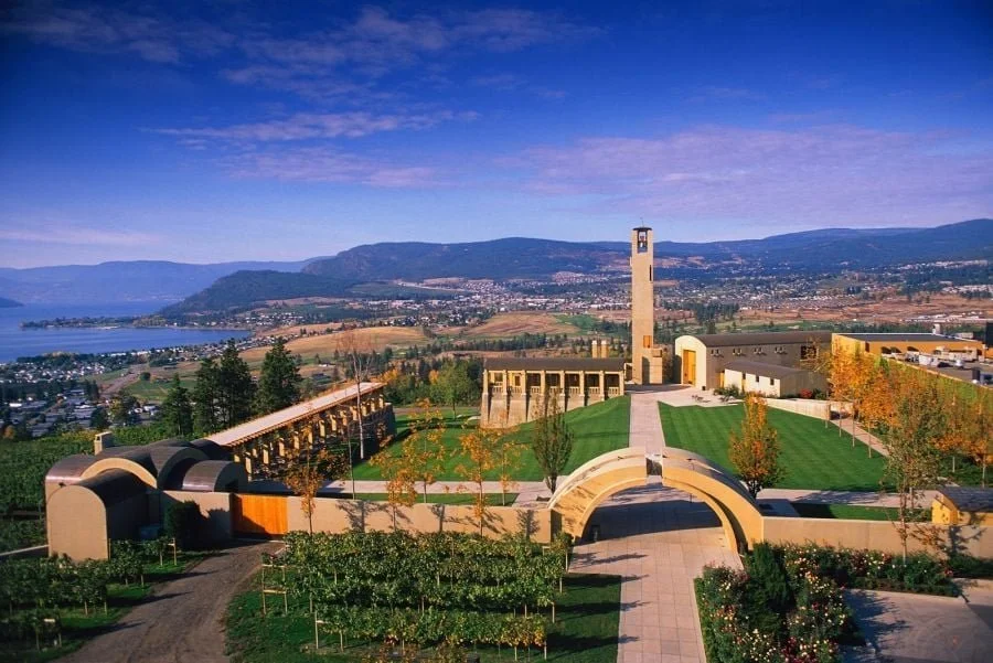 Landscape view of the Oregon State Capitol building, with a tower, greenery, trees, and mountains in the background.