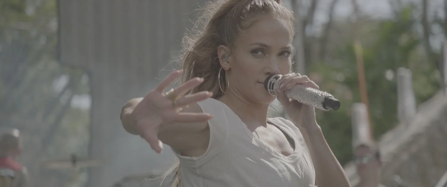 A woman singing into a glittering microphone outdoors